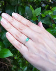 Hand wearing a Colombian emerald ring for mother's day with a leafy background.