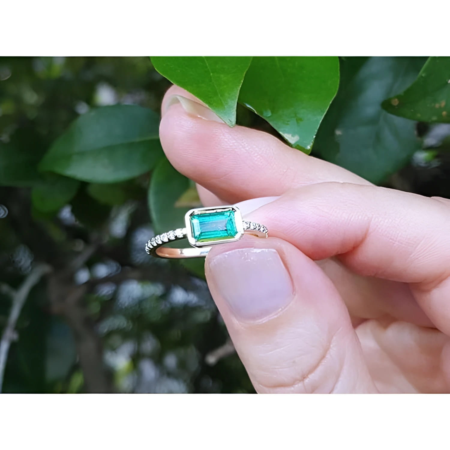 14K yellow gold east-west emerald ring, bezel set, with accent diamonds on the band.