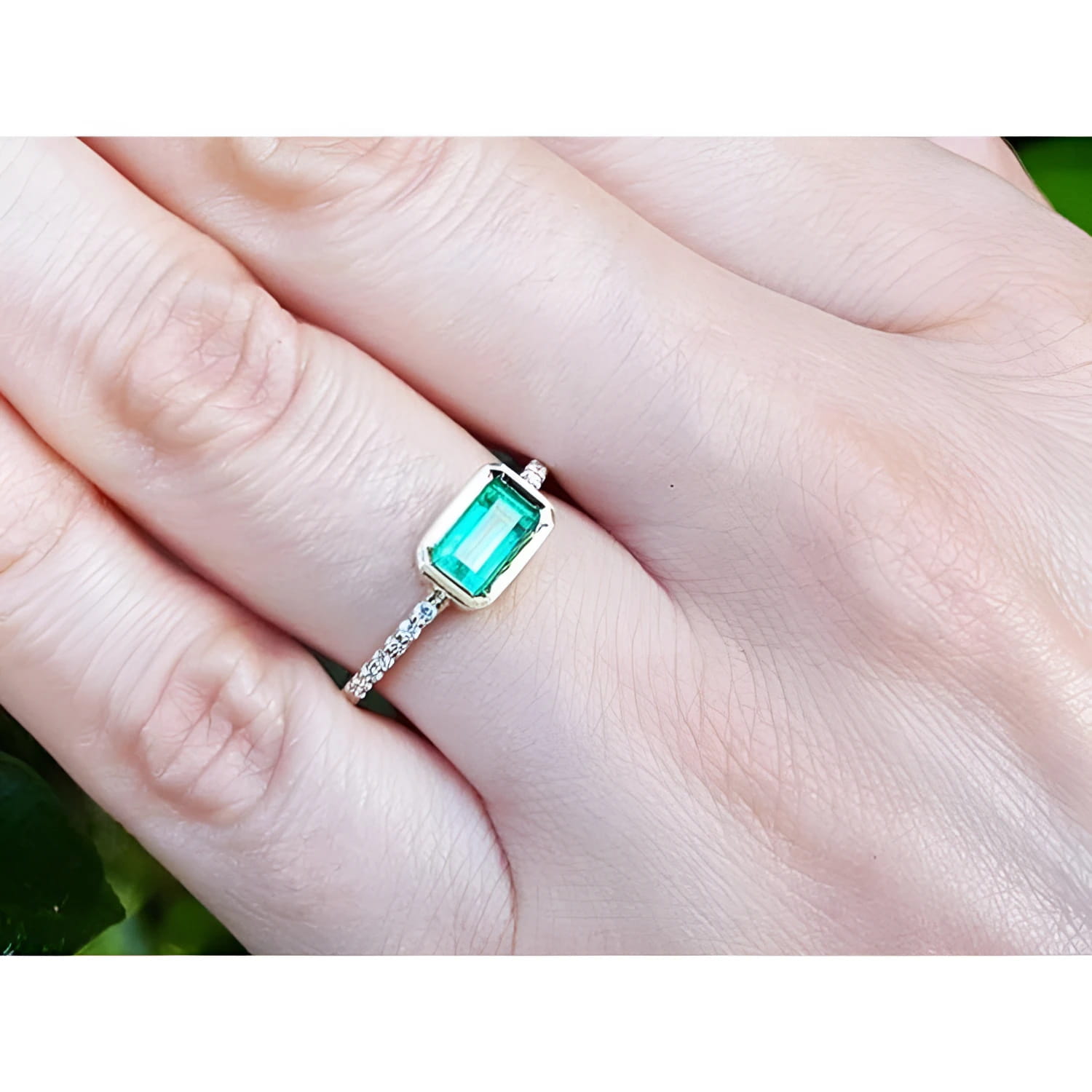 14K yellow gold east-west emerald ring with a bezel-set rectangular emerald and diamond band.