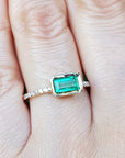 Emerald-cut gemstone ring on a finger with a blurred background