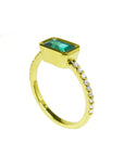 Side profile of a yellow gold emerald ring on a white background.