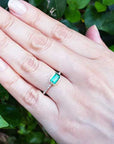 Hand wearing a mother’s day emerald ring the perfect gift for her with a leafy background.
