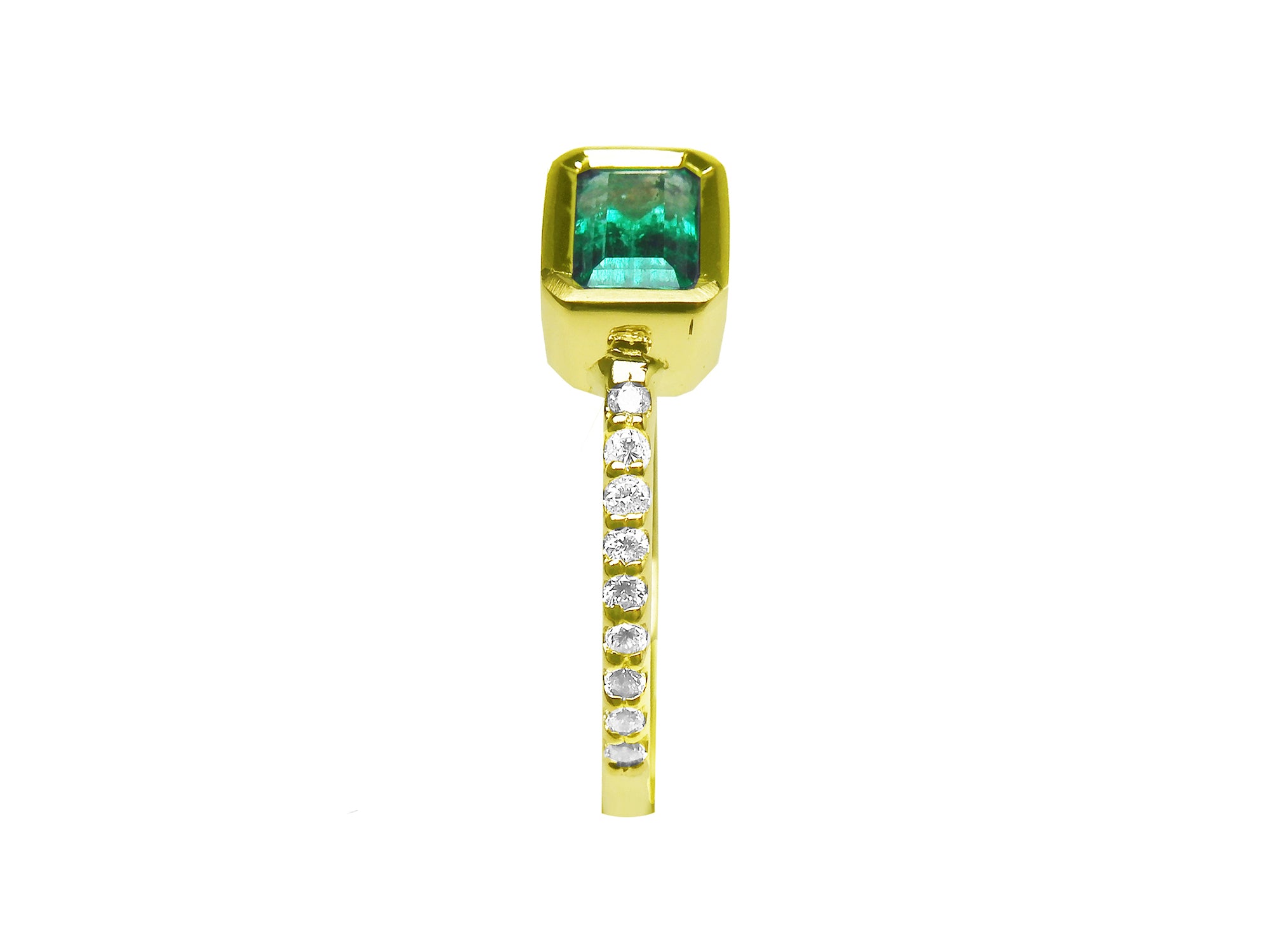 This bezel set emerald ring displays the top and side accent diamonds along the band in yellow gold.