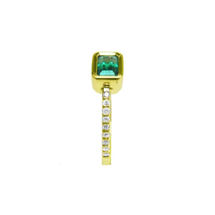 This bezel set emerald ring displays the top and side accent diamonds along the band in yellow gold.