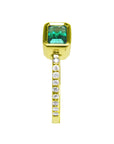 This bezel set emerald ring displays the top and side accent diamonds along the band in yellow gold.