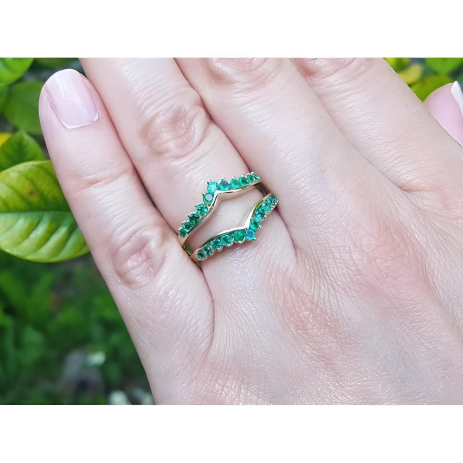 14K yellow gold emerald ring guard with 22 round-cut Colombian emeralds, worn on a finger.