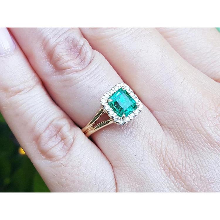 Square emerald and halo diamond ring in yellow gold on a person's hand