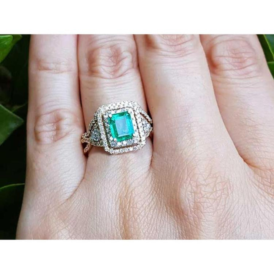 A bridal emerald engagement ring with double halo diamonds in 14k yellow gold.