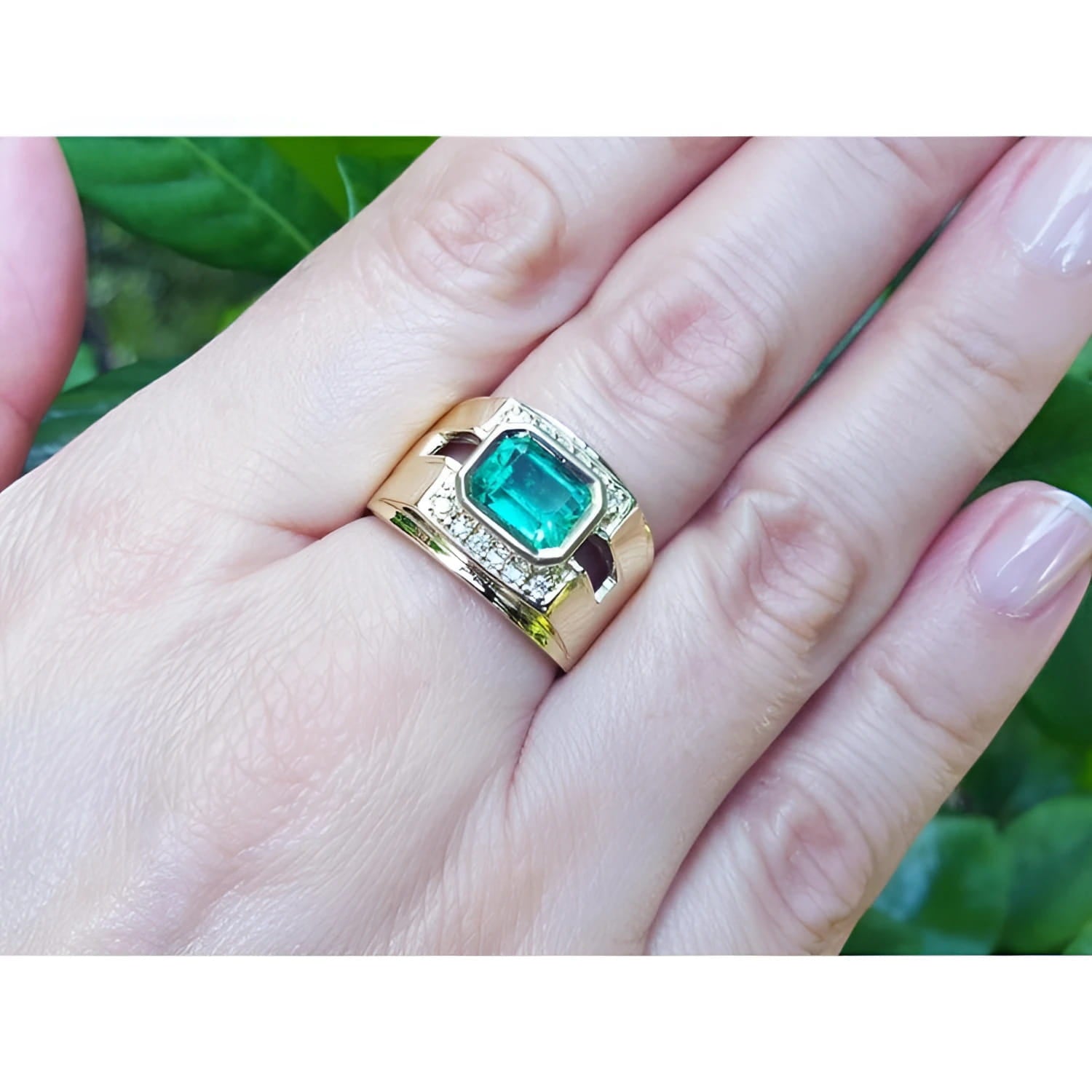 Men's 18K yellow gold ring with a rectangular emerald and surrounding diamonds on a hand.