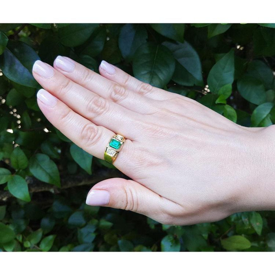 Men's 18K yellow gold ring with a bezel-set Colombian emerald and two prong-set side diamonds.