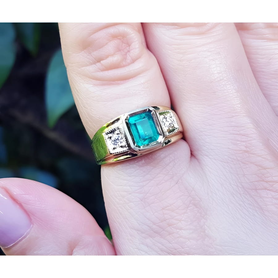 18k yellow gold ring for man with a natural colombian emerald and accent diamonds worn on a finger.
