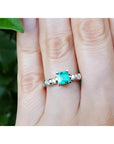 A hand wearing a ring with a natural colombian square emerald with accent diamonds in white gold.