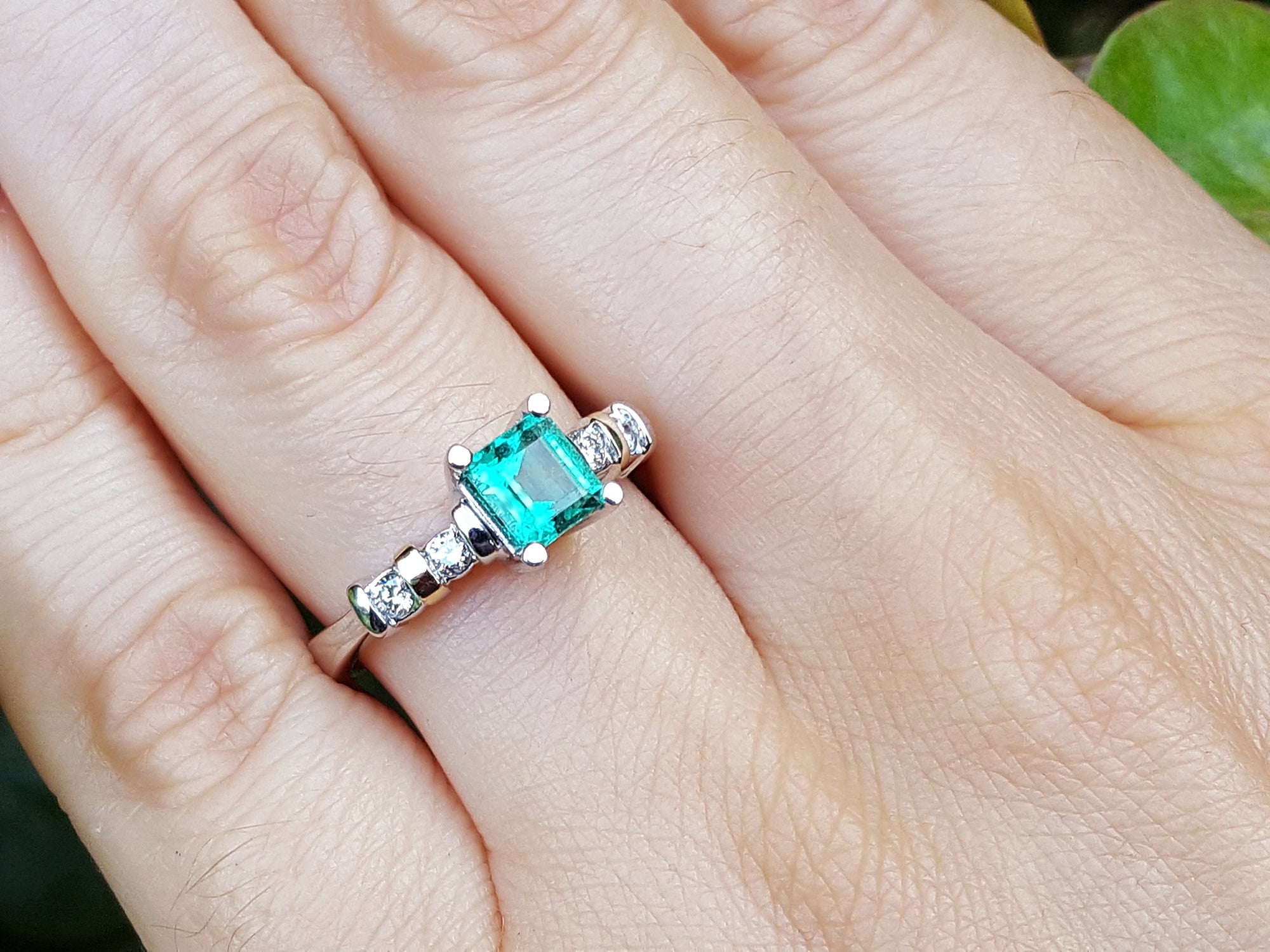Ring with a natural square emerald on a person&#39;s finger.