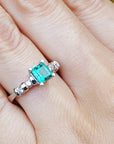 Ring with a natural square emerald on a person's finger.