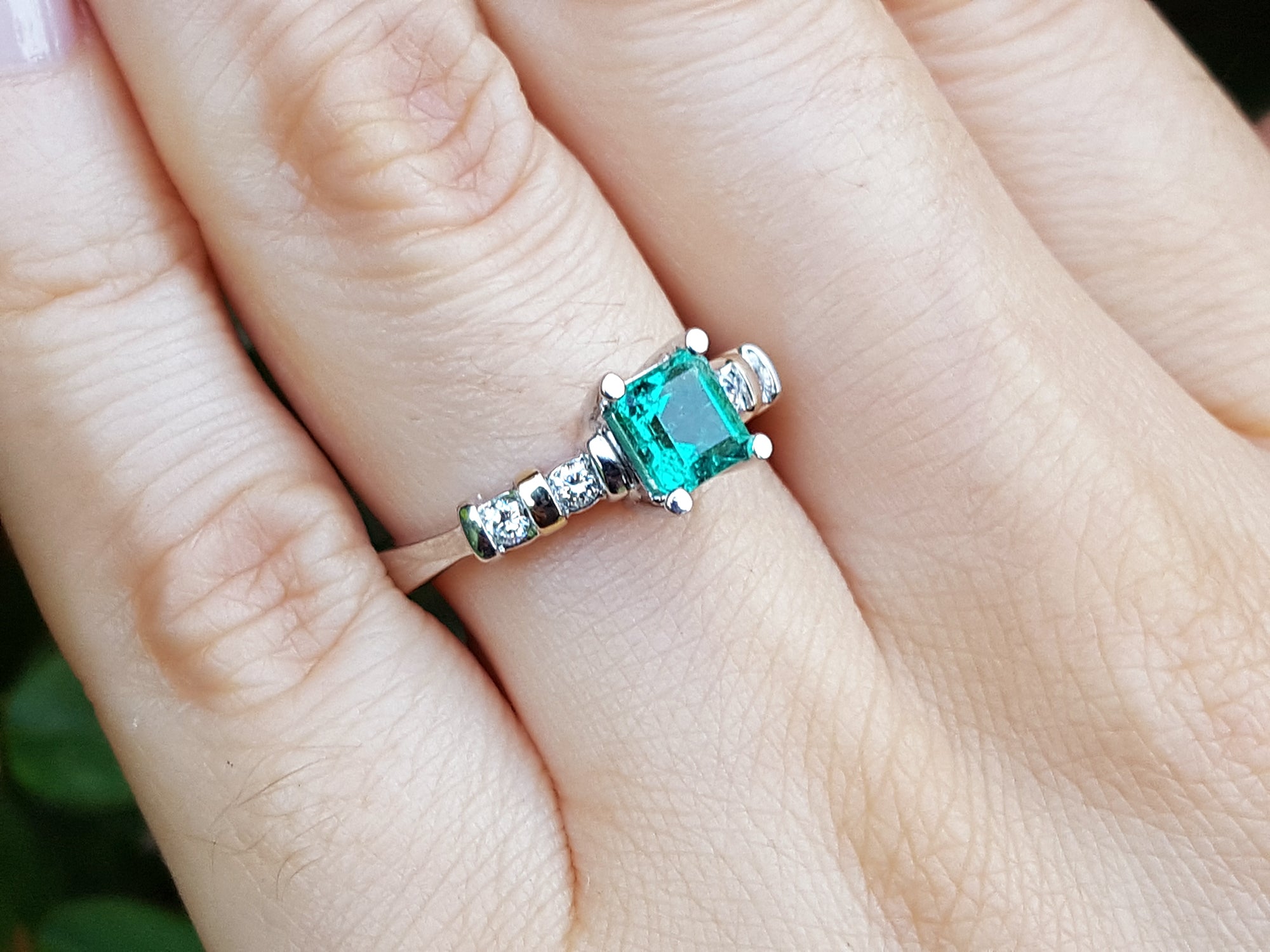 Ring with a Colombian emerald on a person&#39;s finger.