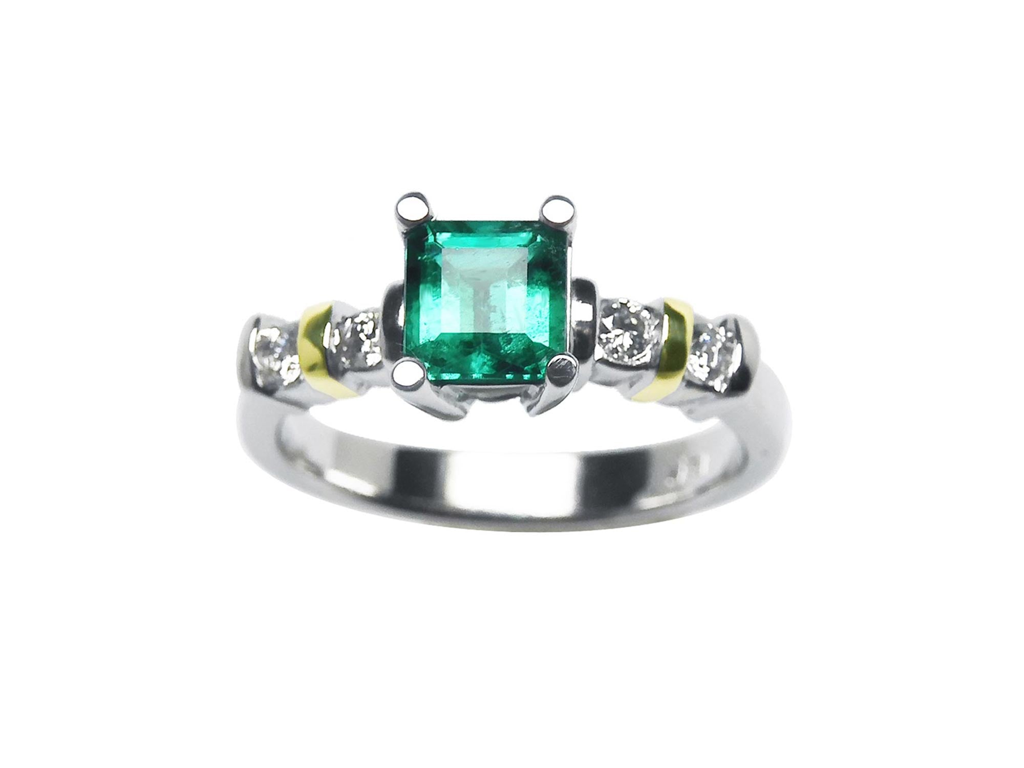 Topside profile view of an emerald and diamonds ring on a white background.