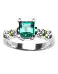 Topside profile view of an emerald and diamonds ring on a white background.