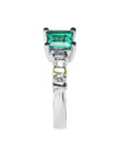 Side profile of a square emerald and round diamonds on the band of the ring.