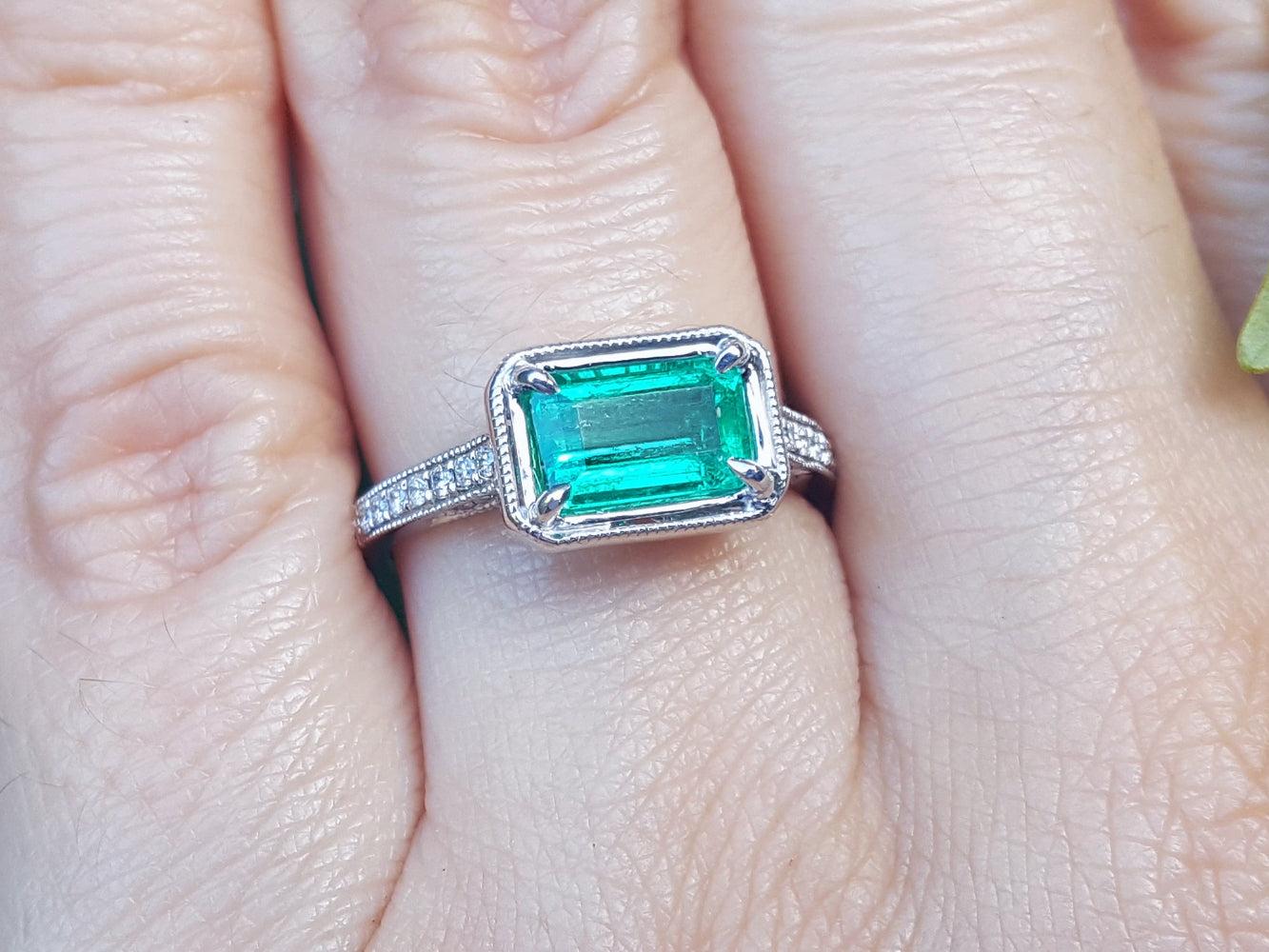 Emerald and accent diamonds ring white gold on a finger