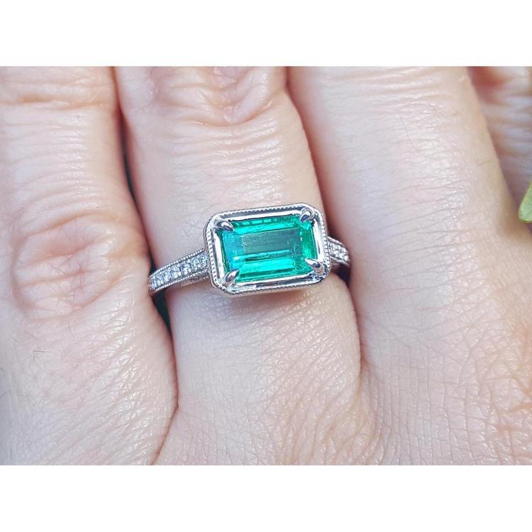 Emerald and accent diamonds ring white gold on a finger