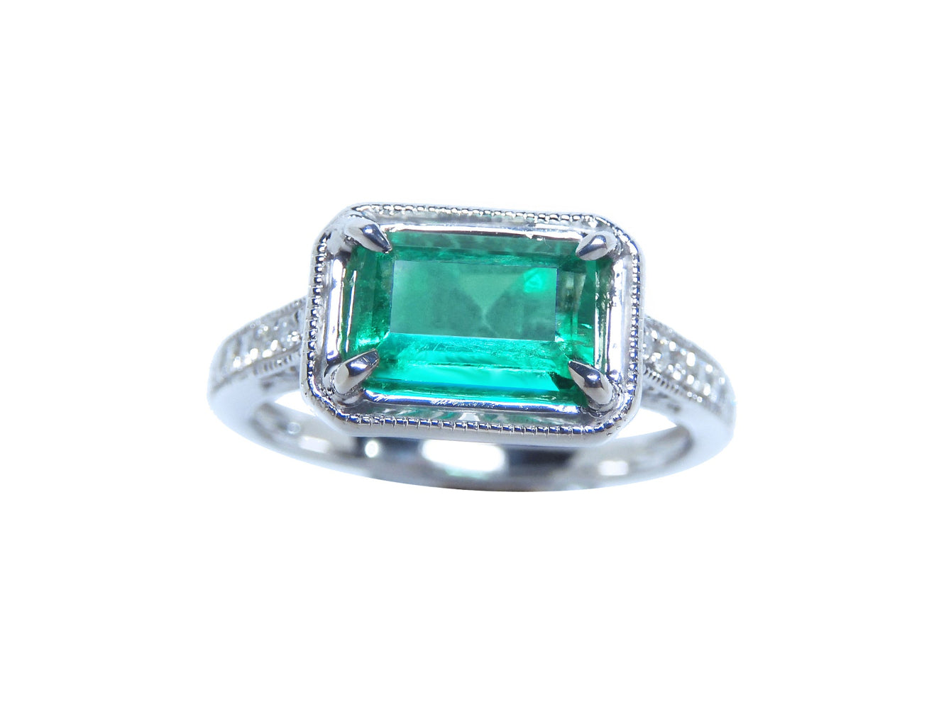 The topside of this natural emerald and diamond ring displays the center of the main gemstone and sides of the band design.