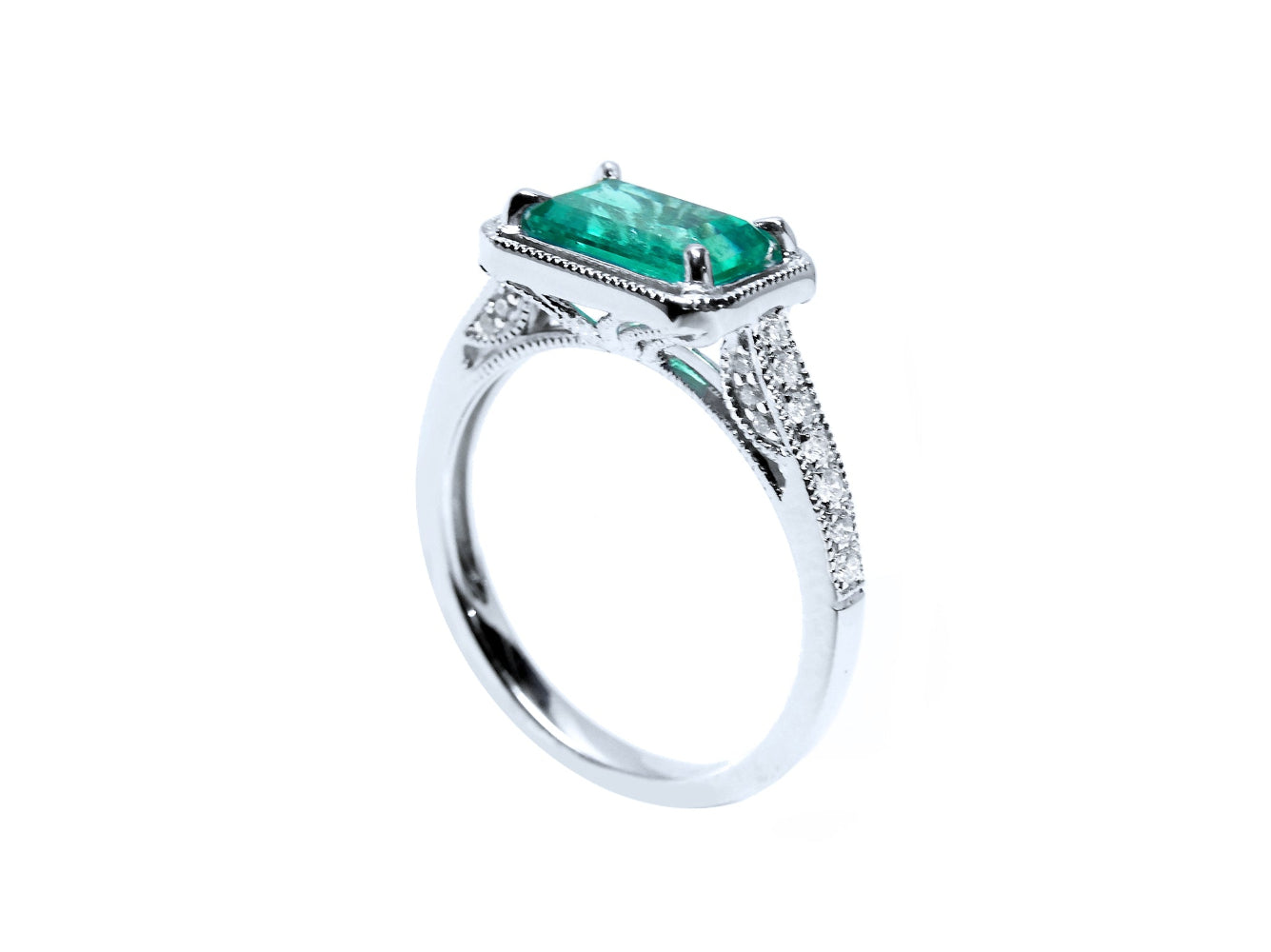 A natural emerald and diamonds ring in white gold displaying the top and partial side view.