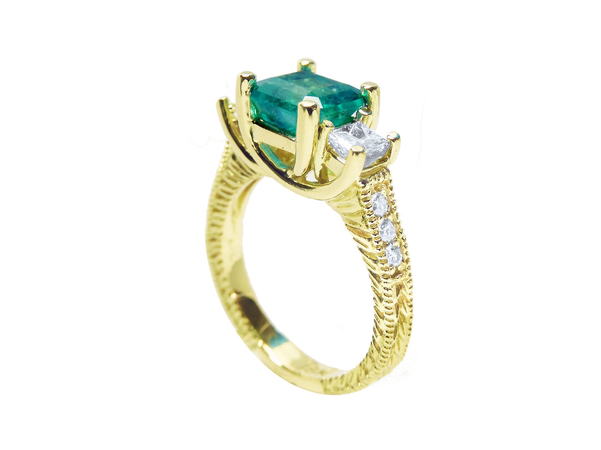 A half side profile of an emerald ring with side princess cut diamonds in 18k yellow gold.
