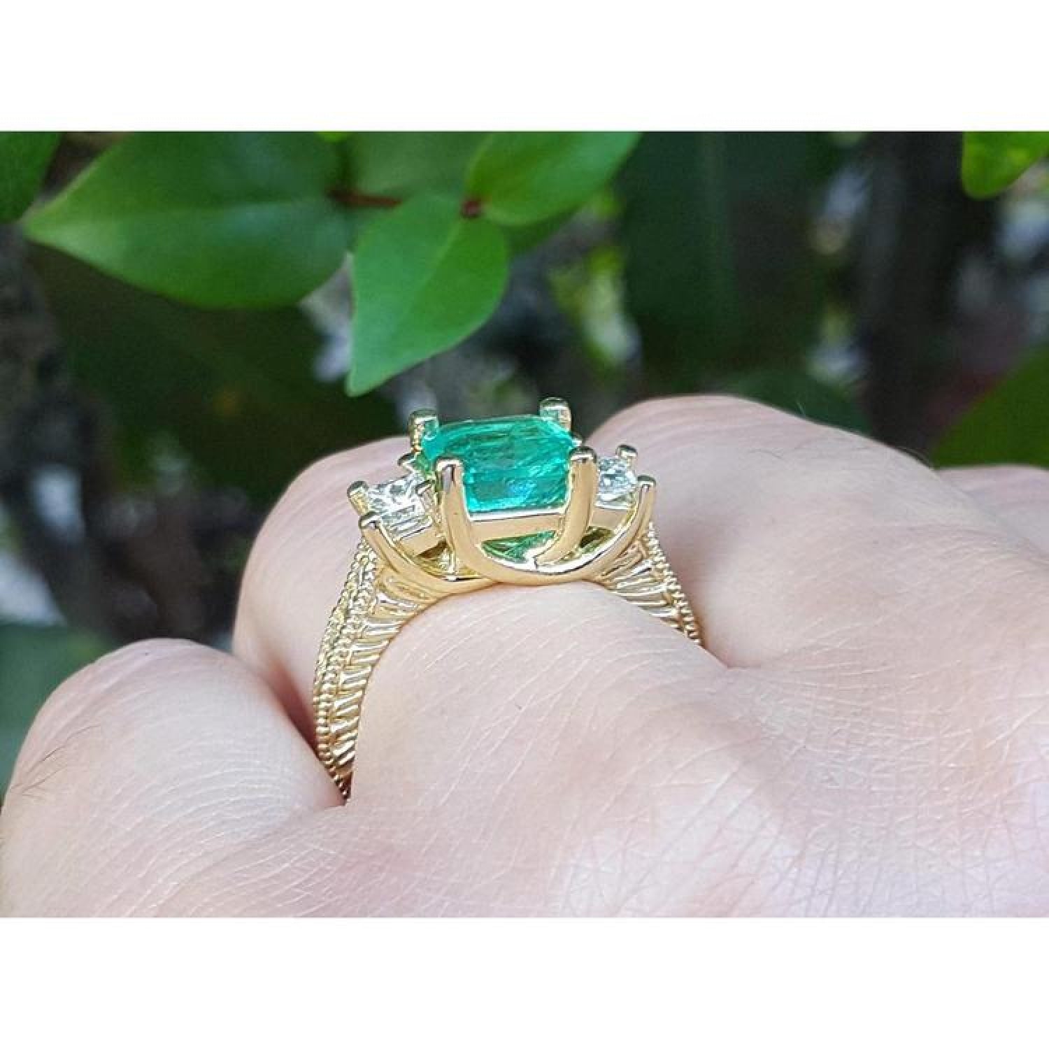 Yellow gold 18K ring with a large emerald cut emerald and two princess cut side diamonds.