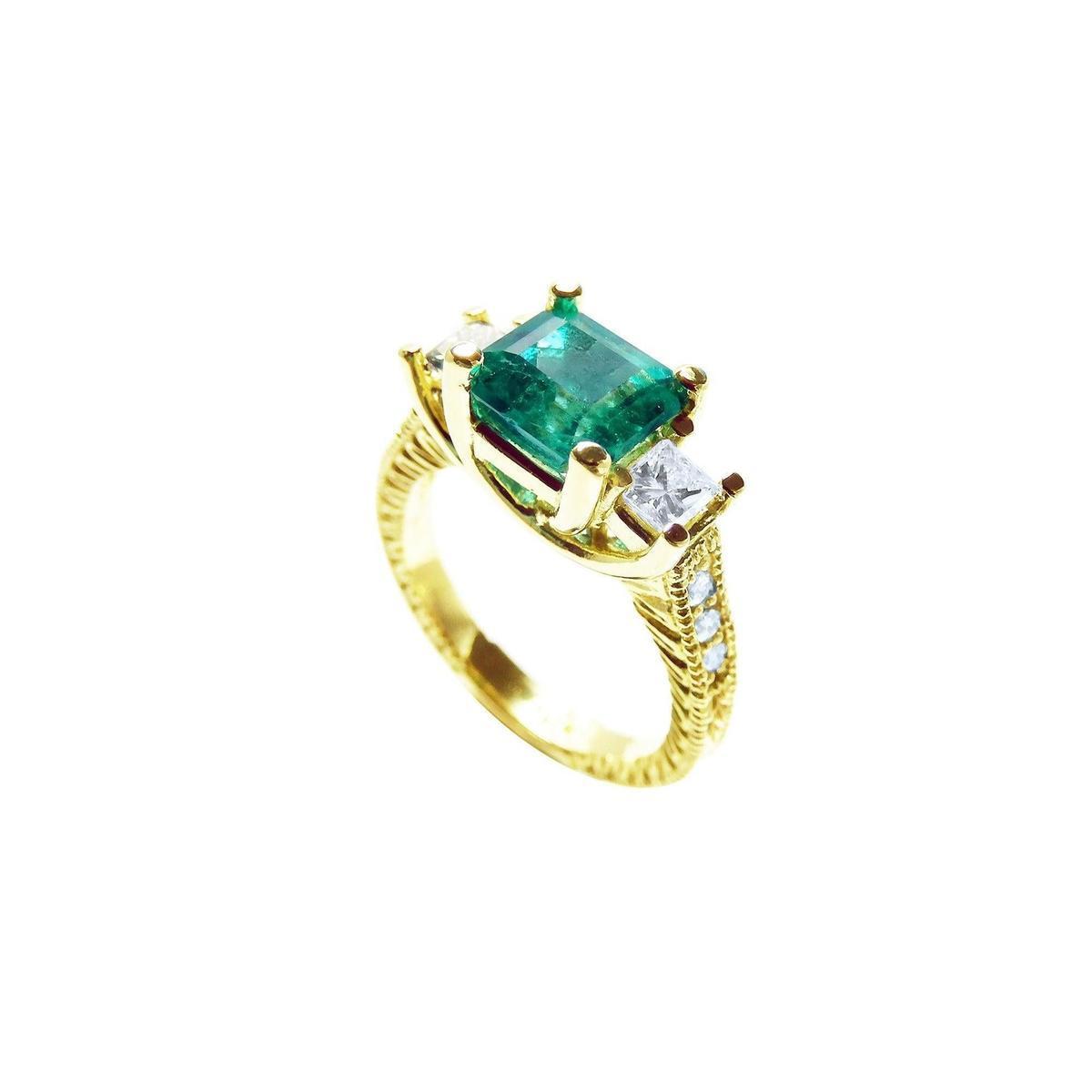 An emerald ring with side princess cut diamonds on a white background.