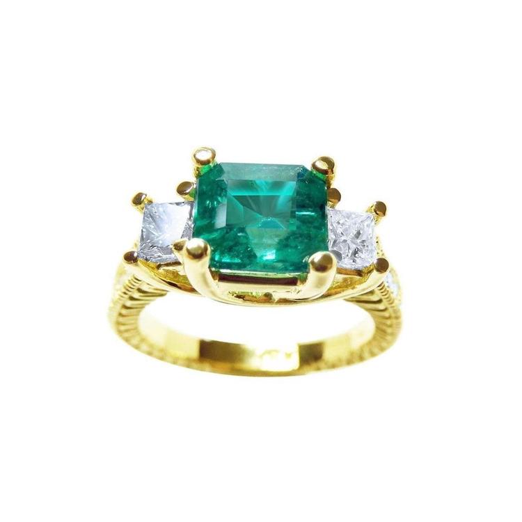 This emerald and princess cut side diamond three stone ring for women is made of 18k yellow gold.