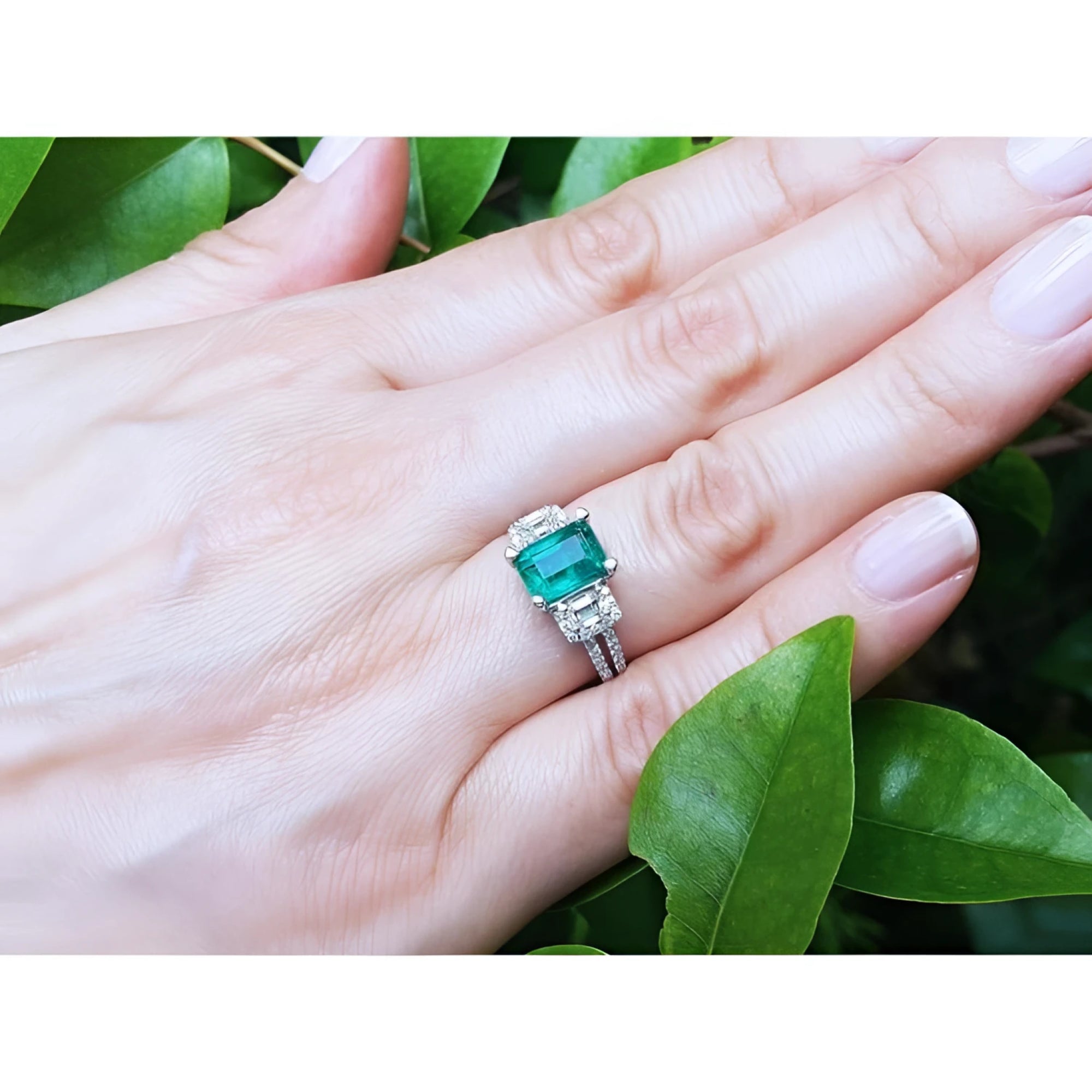 1.88 carat emerald ring with side emerald-cut and round diamonds in 18k white gold on a hand.