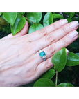 1.88 carat emerald ring with side emerald-cut and round diamonds in 18k white gold on a hand.