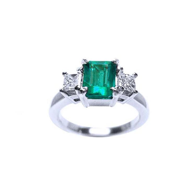 18k white gold three-stone ring with a rectangular emerald and two princess-cut side diamonds.