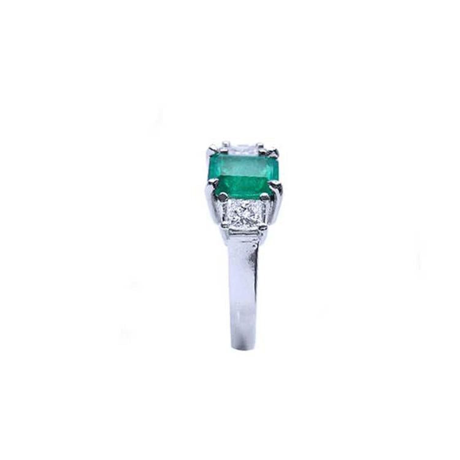 18k white gold three-stone ring with a rectangular emerald and two princess-cut side diamonds.