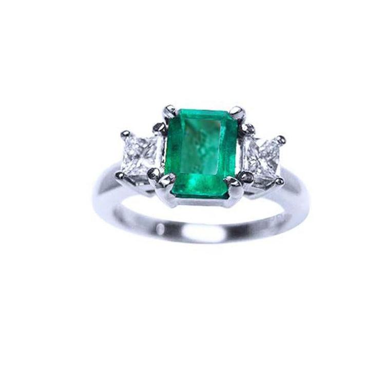 A three stone natural emerald ring for women with princess cut side diamonds in 14k white gold.