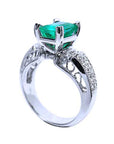 A half underside view of an emerald and diamond engagement ring, gallery visible.