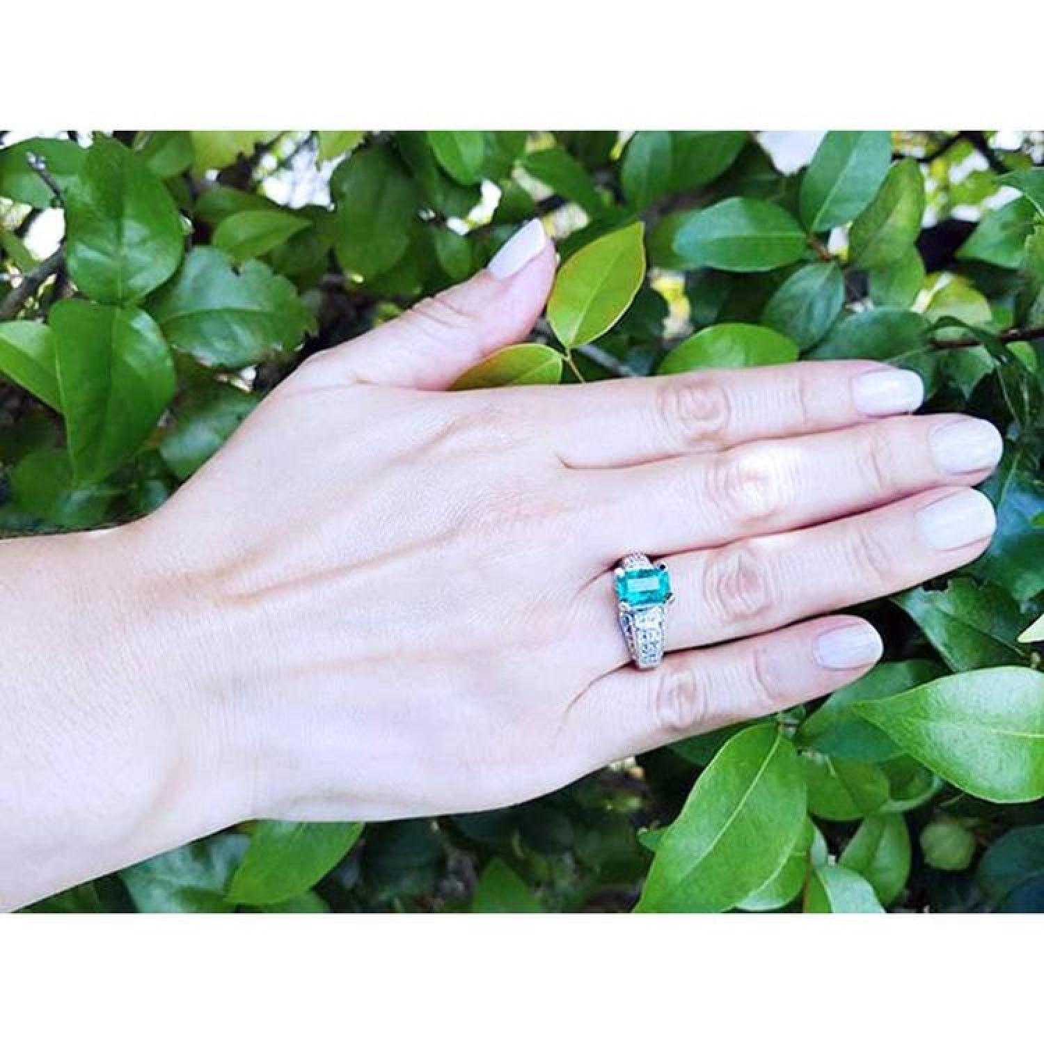 Emerald-cut emerald ring for women in 18K white gold with diamond accents, worn on a hand.