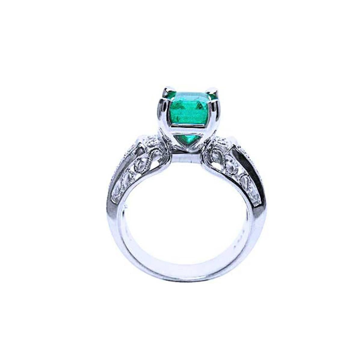 Ring with an emerald gemstone and diamond accents on a lateral position top and gallery visibles.