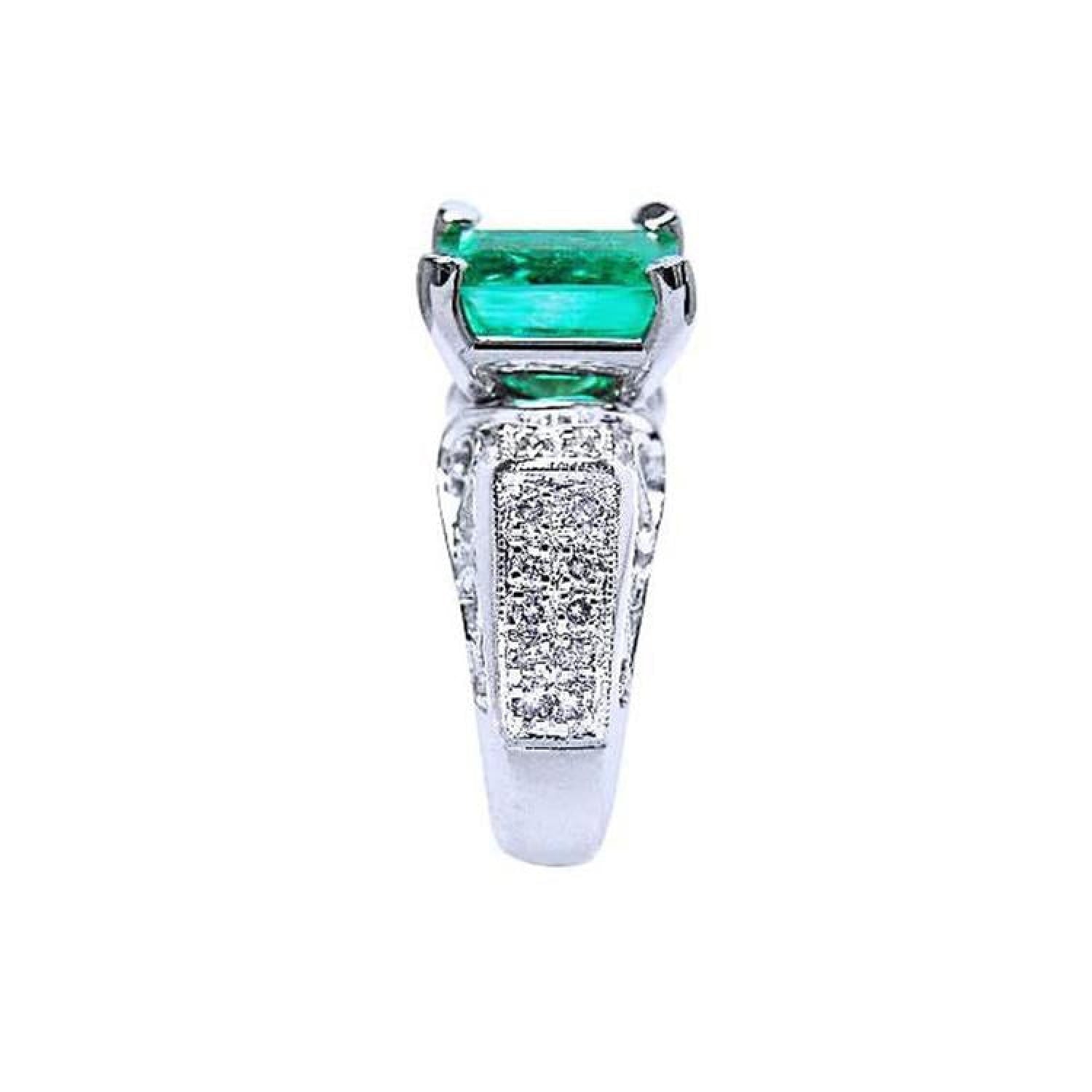 Emerald-cut Colombian emerald ring with diamond-encrusted 18K white gold band.