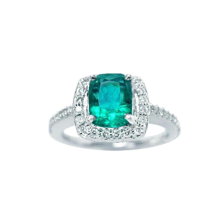 This cushion cut emerald ring for women is adorned with natural diamonds encircling the emerald in white gold