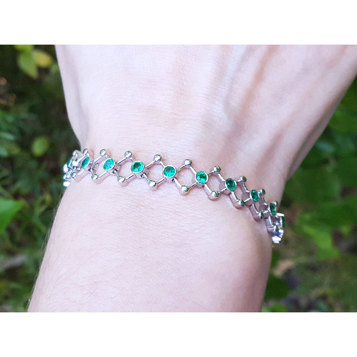 Emerald bracelet for women round cut natural Colombian emeralds 14k white gold on a wrist against a natural background.
