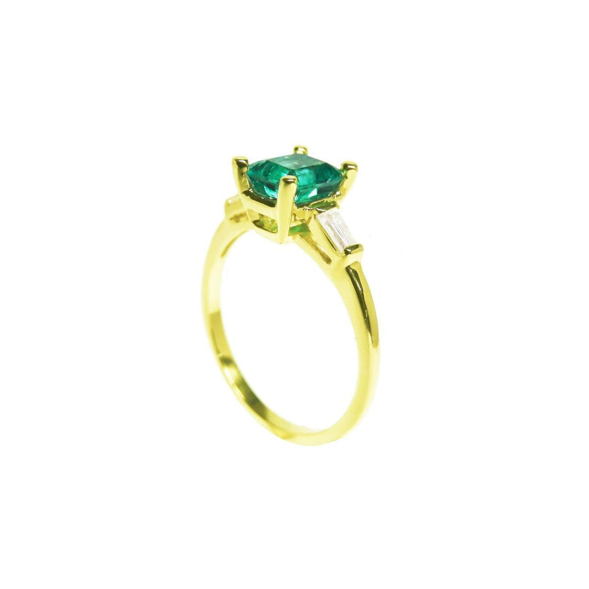 Side view of a yellow gold emerald and side baguette diamond ring