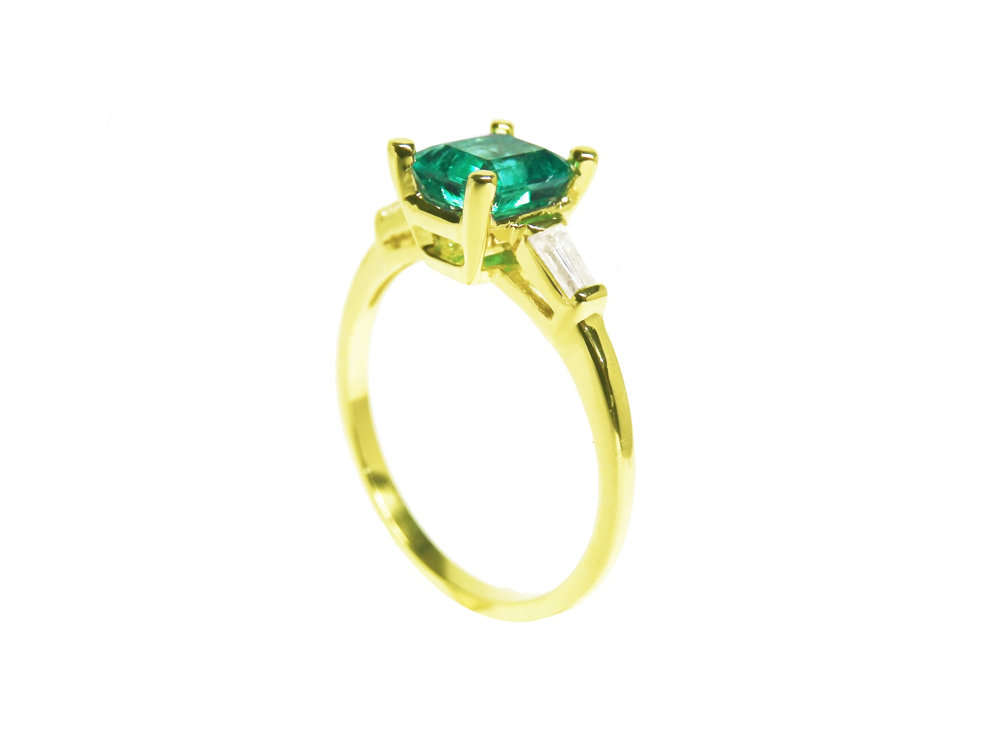 Side view of a yellow gold emerald and side baguette diamond ring