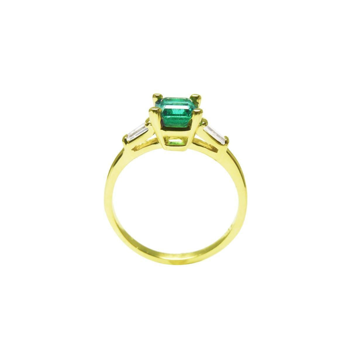 A Colombian emerald on top with side baguettes and gallery gold ring profile visibles including the band.