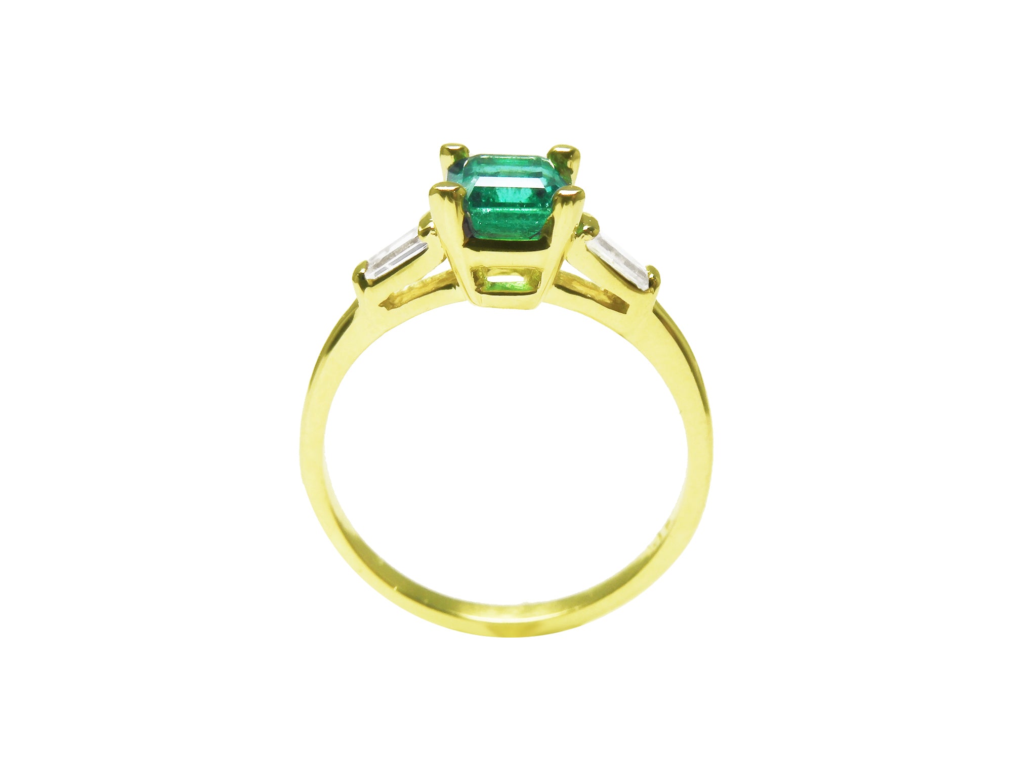 A Colombian emerald on top with side baguettes and gallery gold ring profile visibles including the band.
