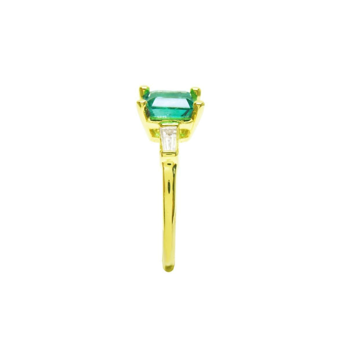 This yellow gold emerald ring shows its side profile, on top the square emerald, baguette diamond and band ring downside.