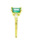 This yellow gold emerald ring shows its side profile, on top the square emerald, baguette diamond and band ring downside.