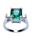 An emerald-cut real Colombian emerald ring in white gold top and partial gallery view.