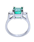 A detailed view of an emerald and princess-cut diamond ring, highlighting the top, side gallery, and band.