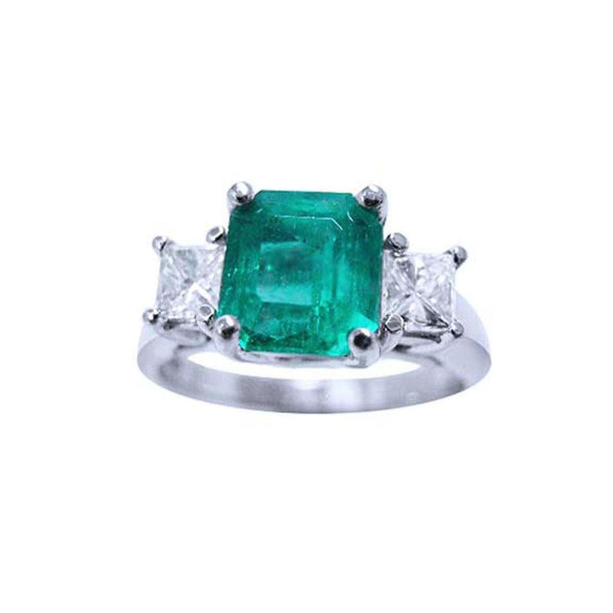 A top side view of an emerald and princess cut side diamonds ring in white gold.